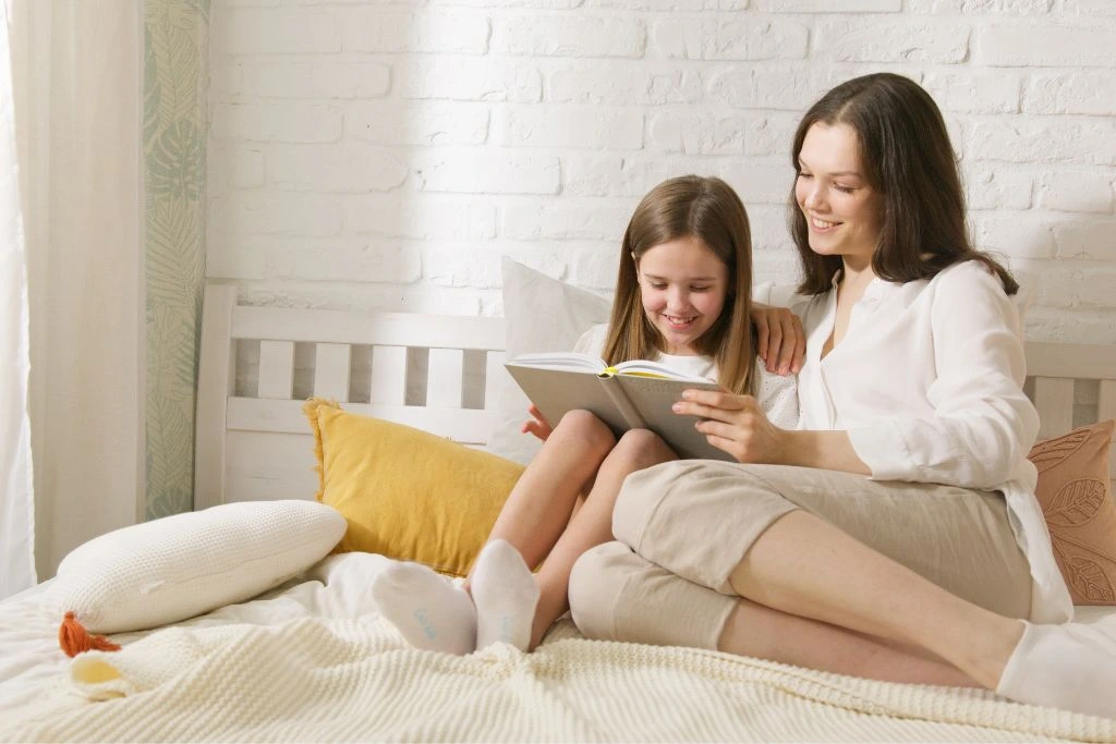 Mom and Daughter reading a book in bed