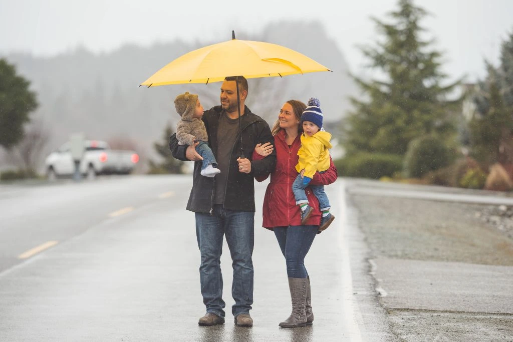 A family holding their children and an umbrella in the rain