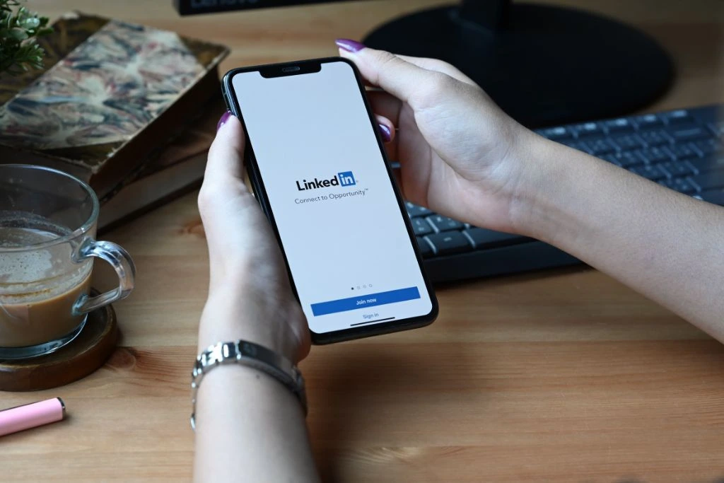 A phone being held with the app LinkedIn on it.