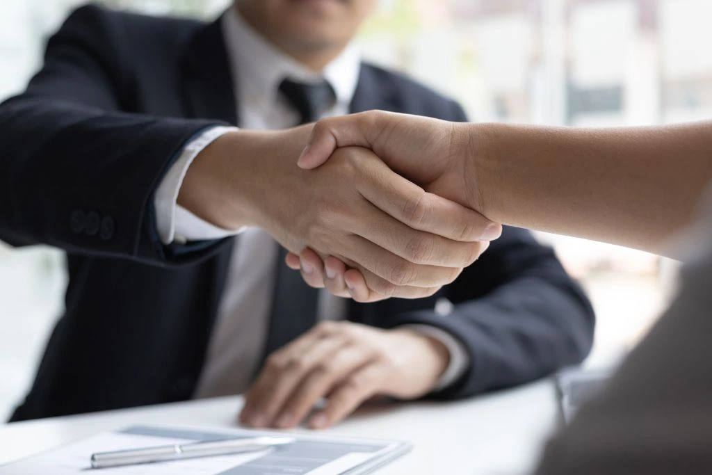 A photo that depicts a man shaking a hand that seems to be congratulatory