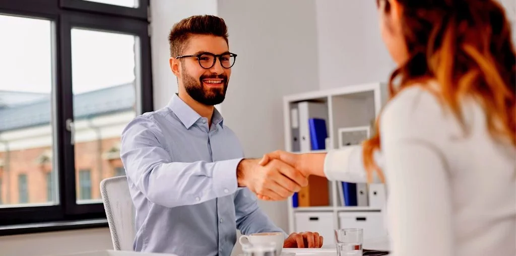 job interview session with a boy smiling while handshaking with a girl employee