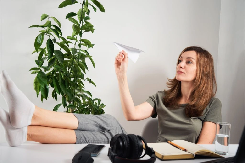 woman sitting at her desk and flying paper planes