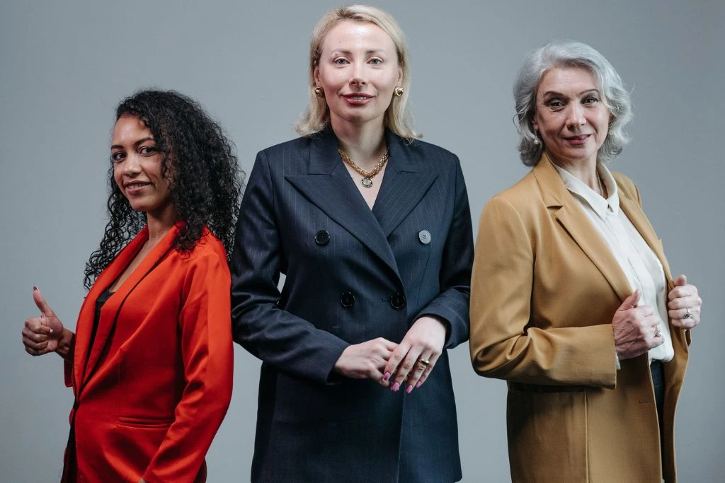 3 women wearing different kinds of office attire on a grey background