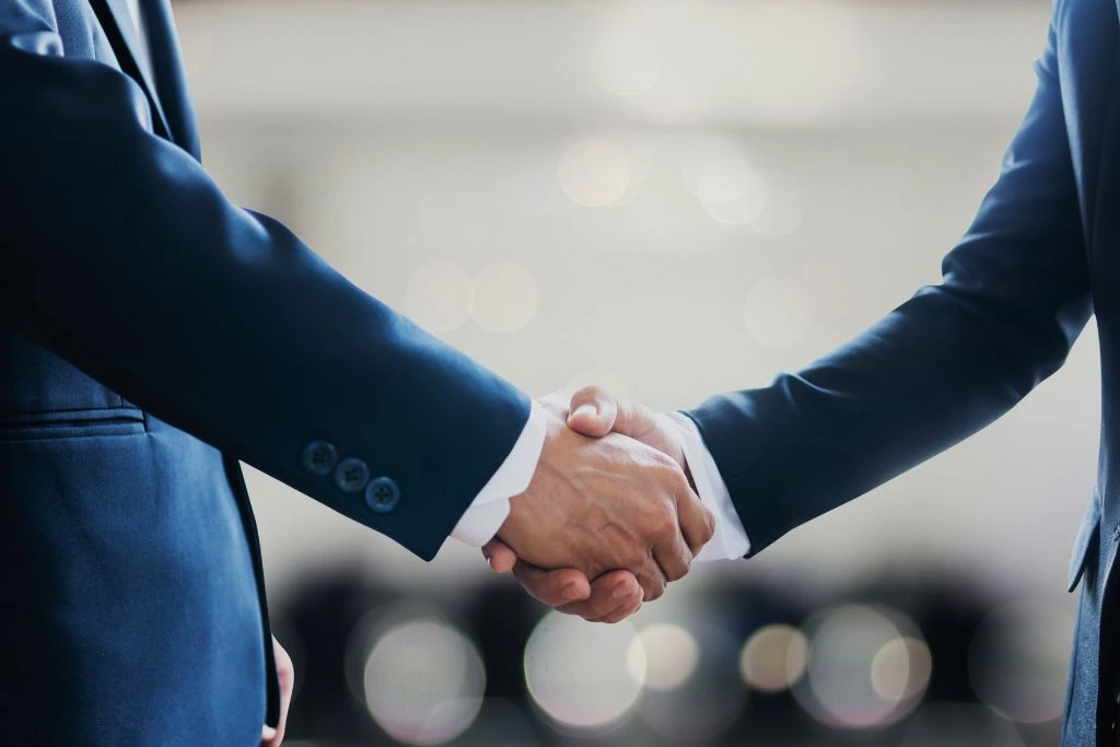 Two men in business suits shaking their hands