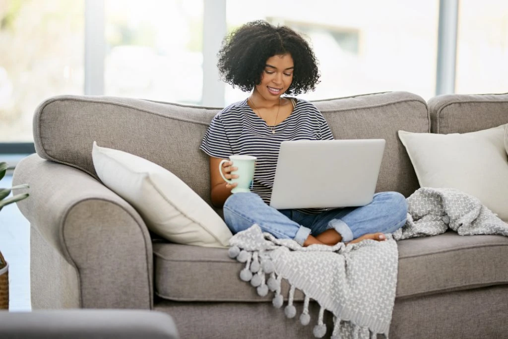 woman sitting on her couch while working on her laptop