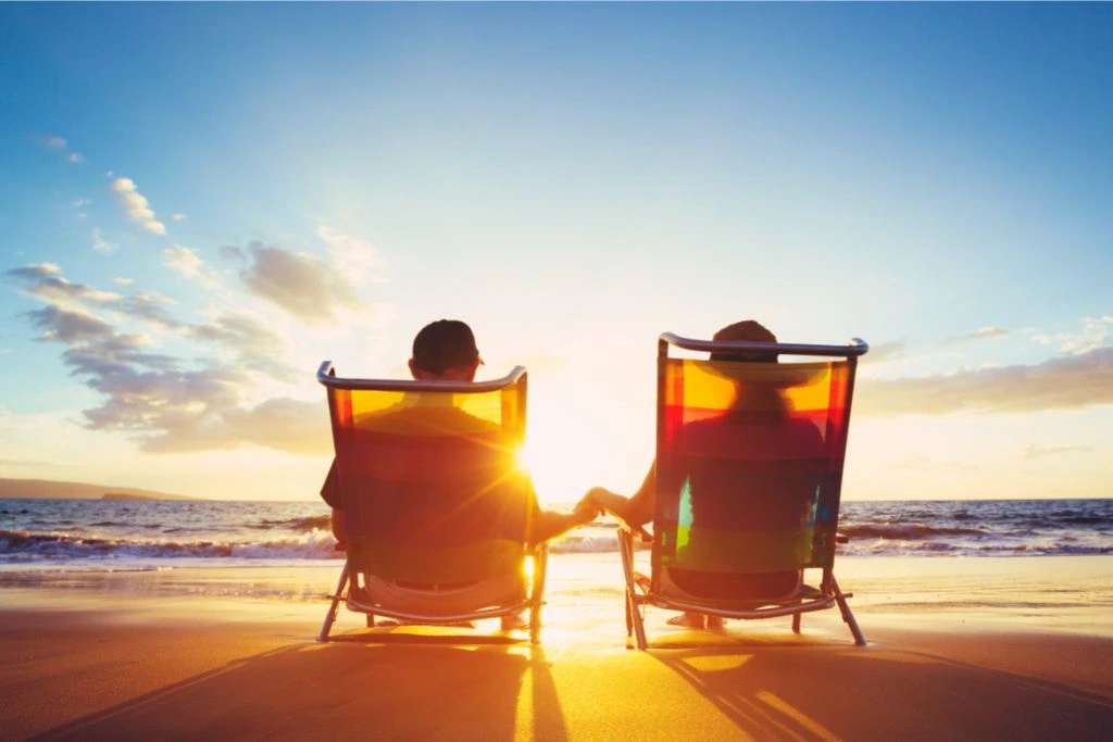 couple sitting on lounger chair watching the sunset at the beach