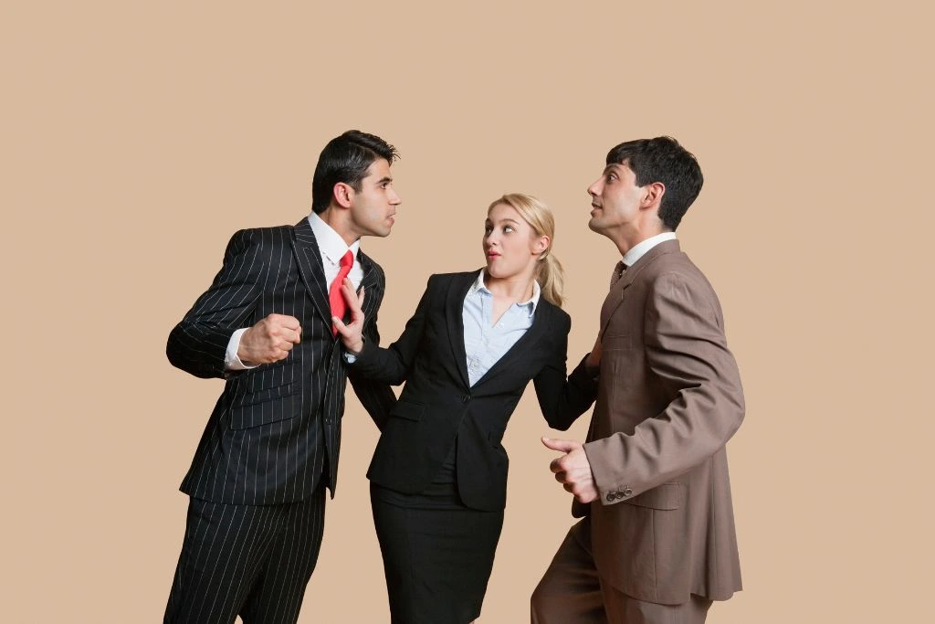 A woman at the middle trying to stop an argument between two male co-workers