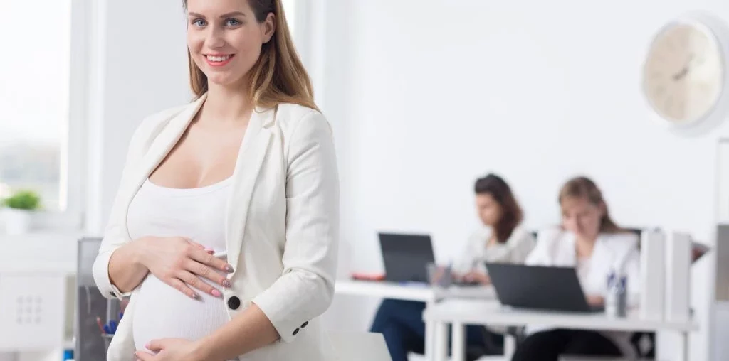 pregnant woman in office attire in a white office