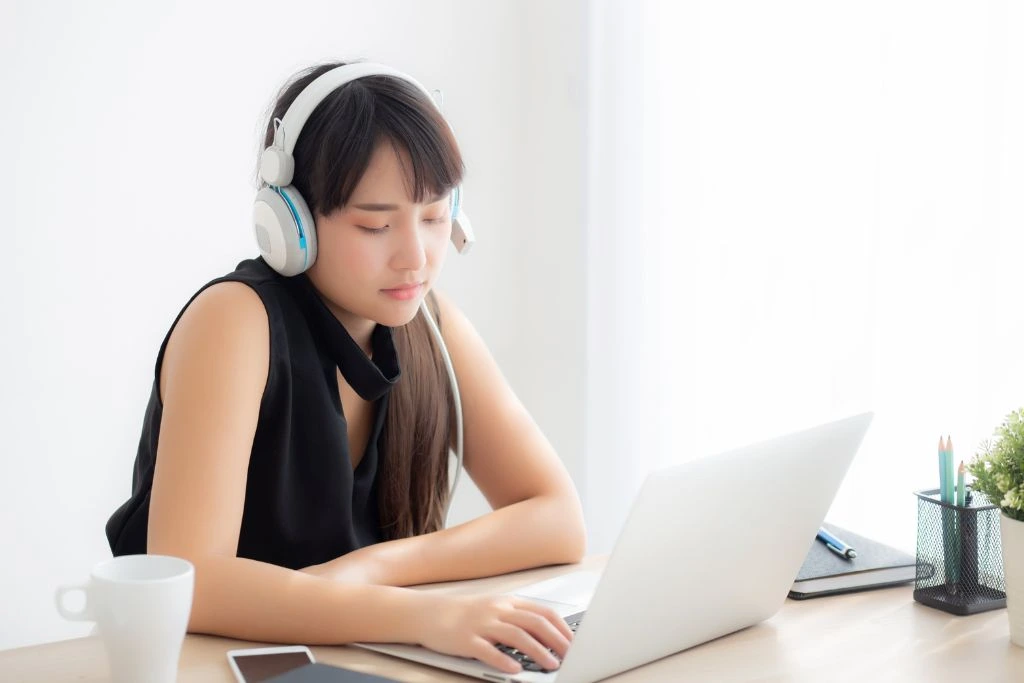 A woman in front of her laptop while listening to music