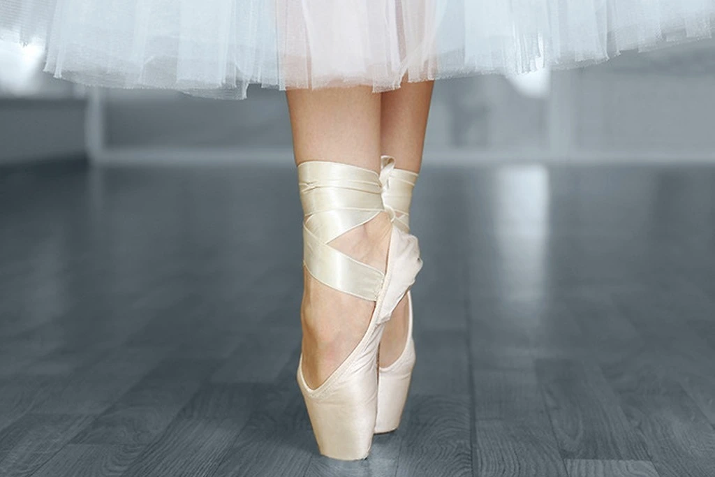 A person tip toeing on ballet shoes