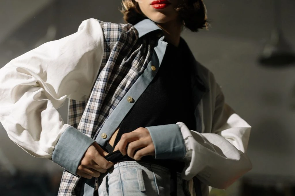 A woman dressed in a white jacket with a gray checkered vest and fashionable gray pants