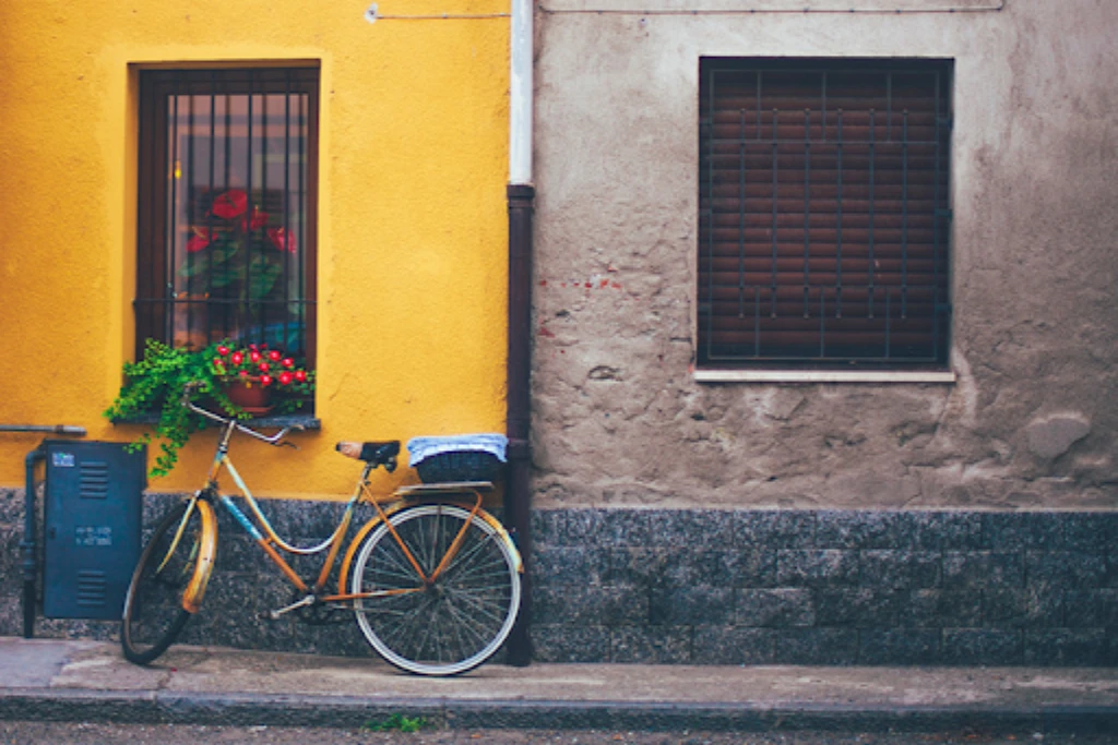 bike on the sidewalk leaning against a yellow wall