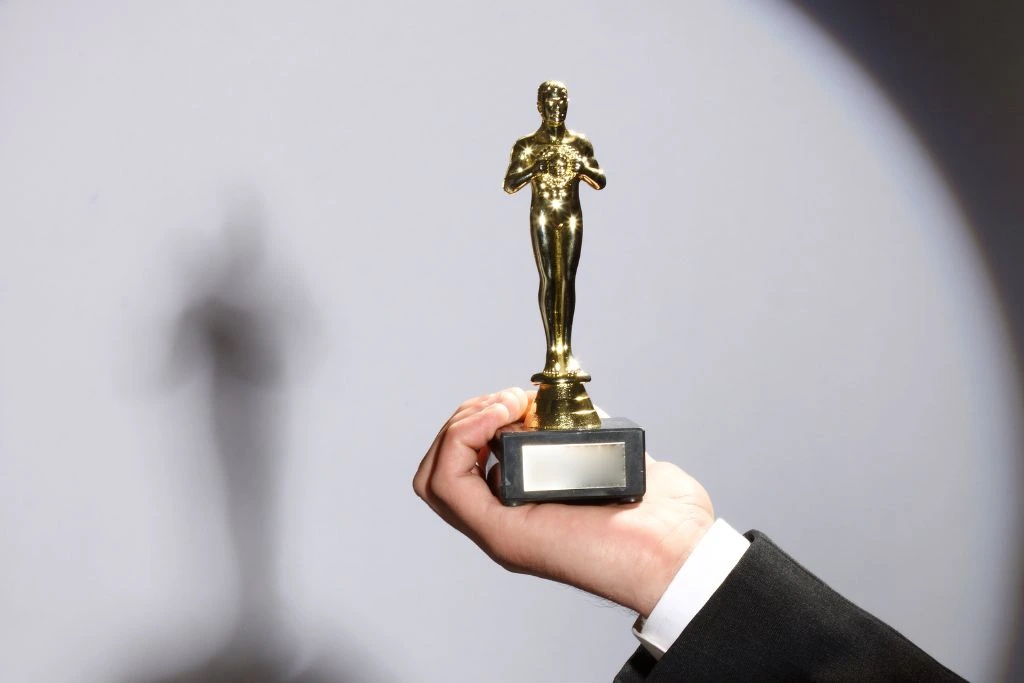 A person holding an Oscar award with one hand