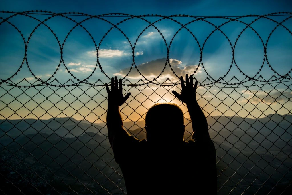 A person holding on the fence