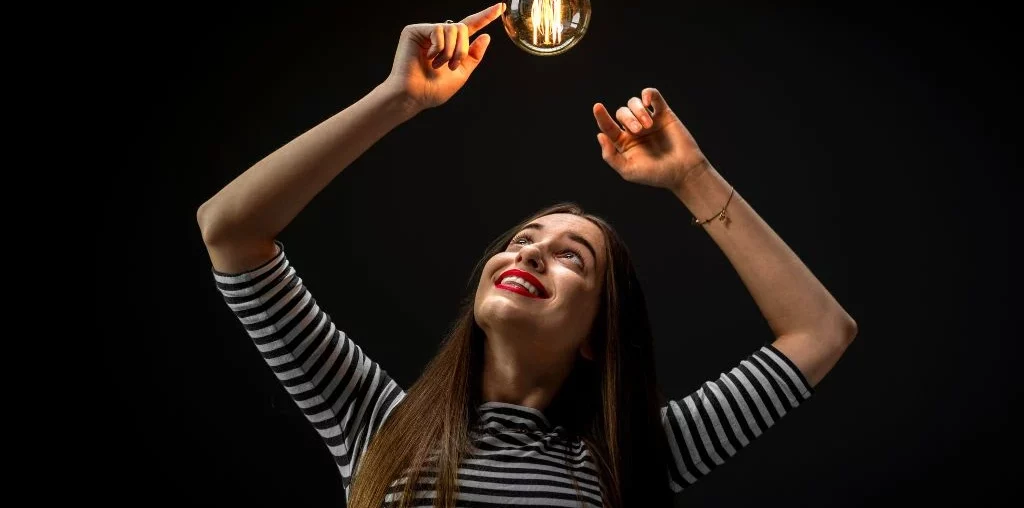woman touching lightbulb above her head