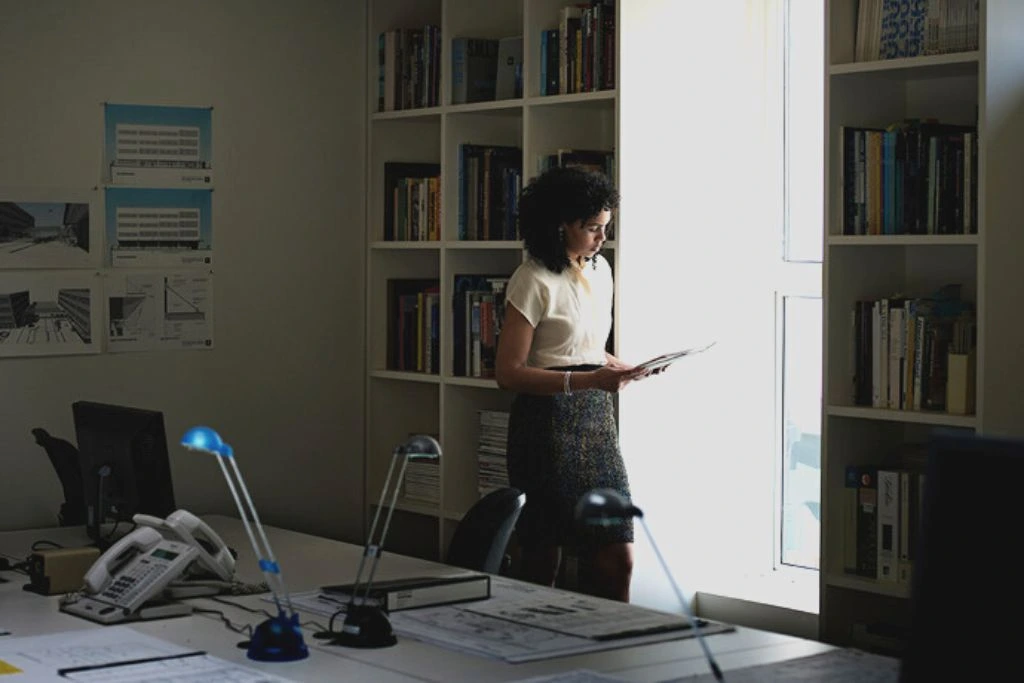 A woman is holding and reading a book inside an office library