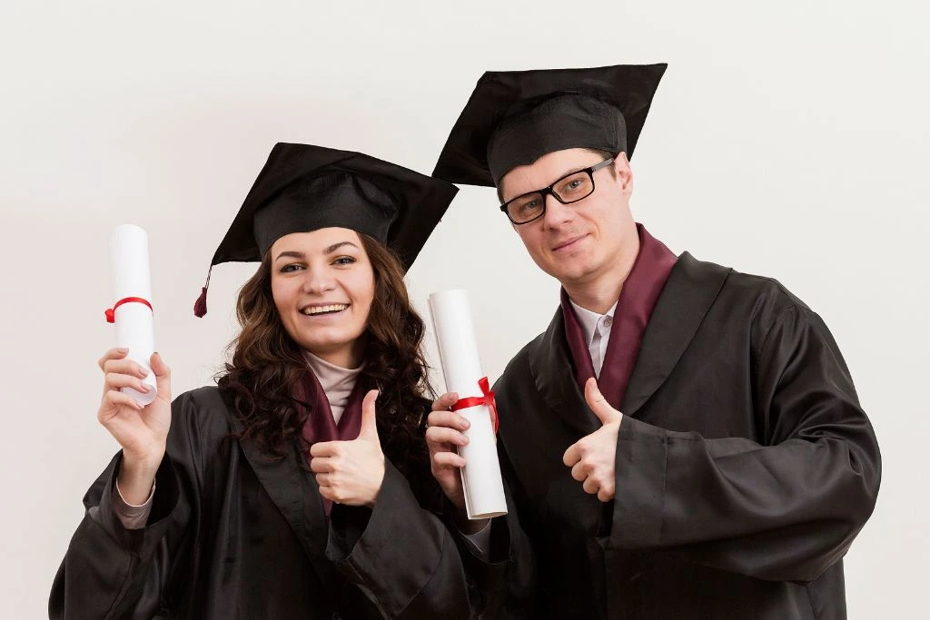 A man and woman holding their diploma