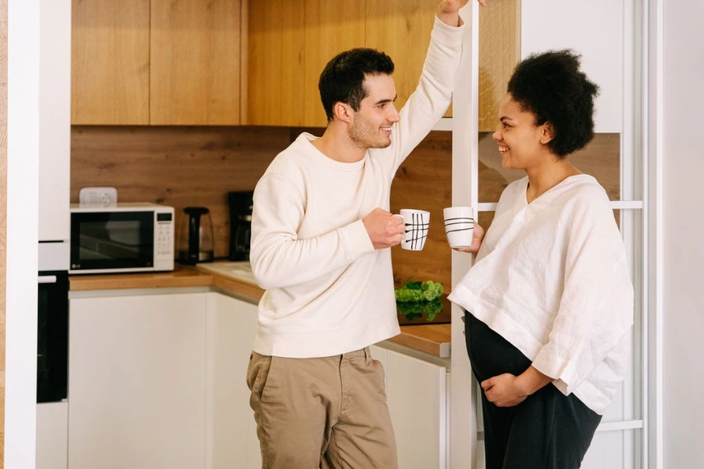 A man talking to a pregnant woman in the pantry