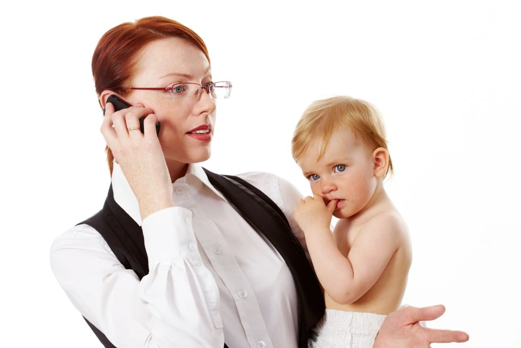 woman in business suit talking on her phone and holding a baby