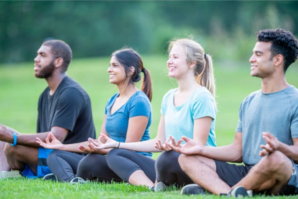 group of athletes meditating on the grass