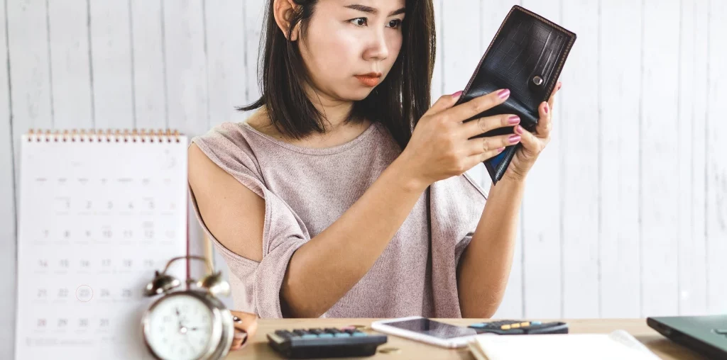 woman looking at her wallet looking frustrated
