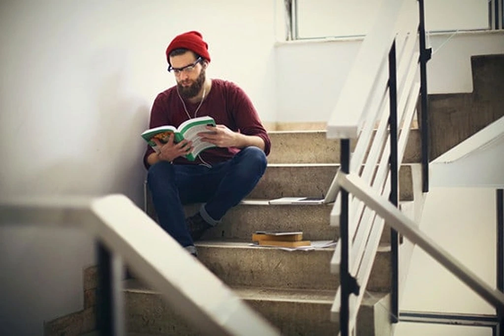 A man reading a book on the stairs