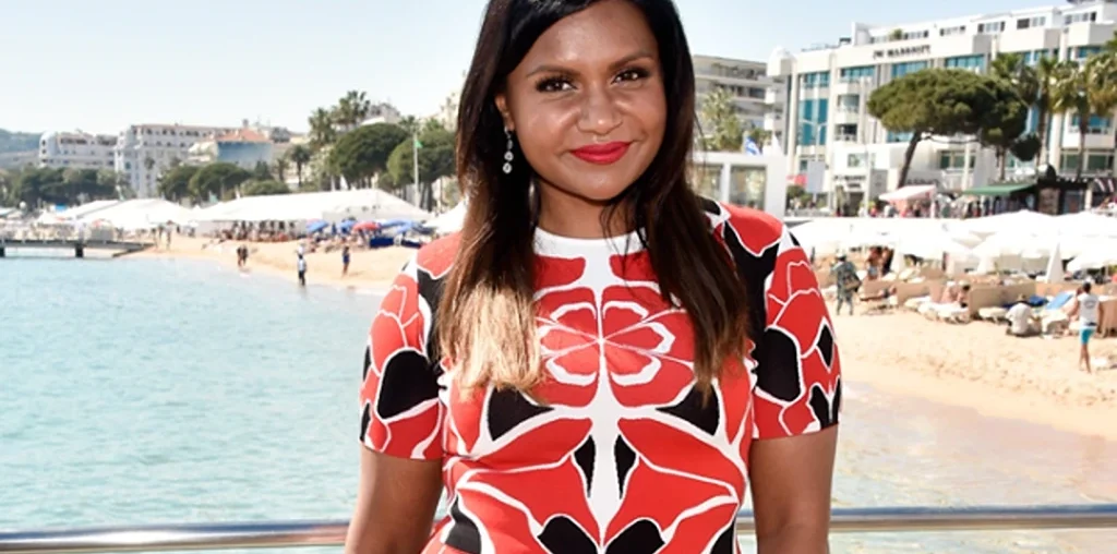 mindy kaling posing with an ocean behind her