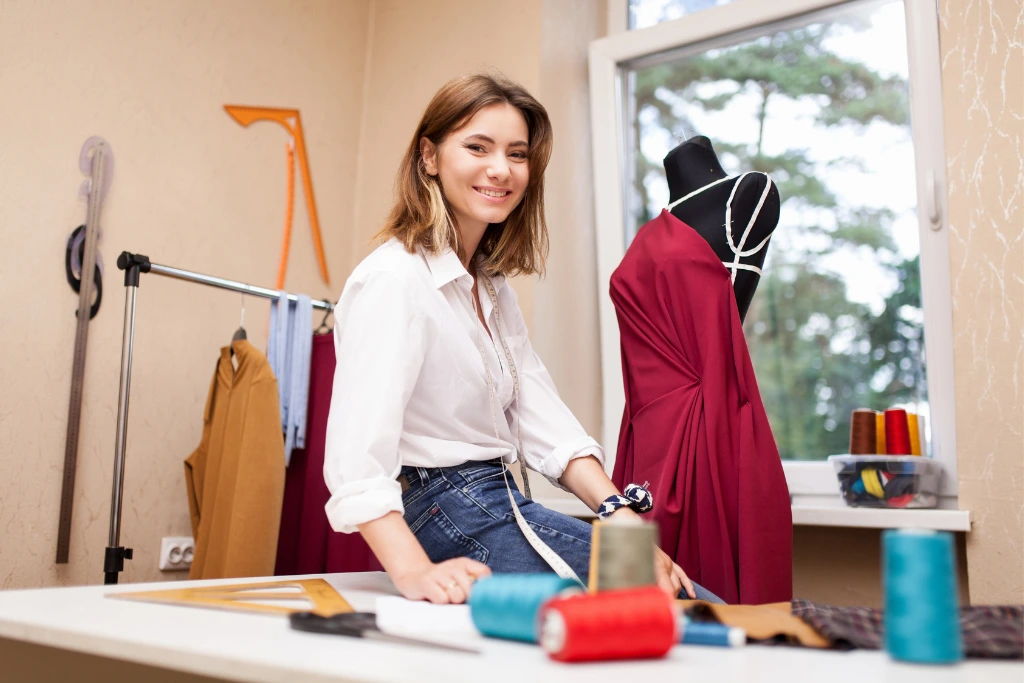 a fashion designer sitting on the table with her work on the background
