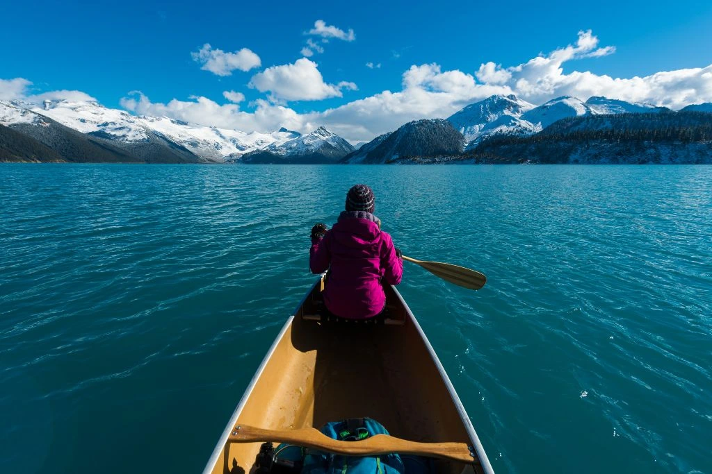 A woman paddling a boat towards a great lake