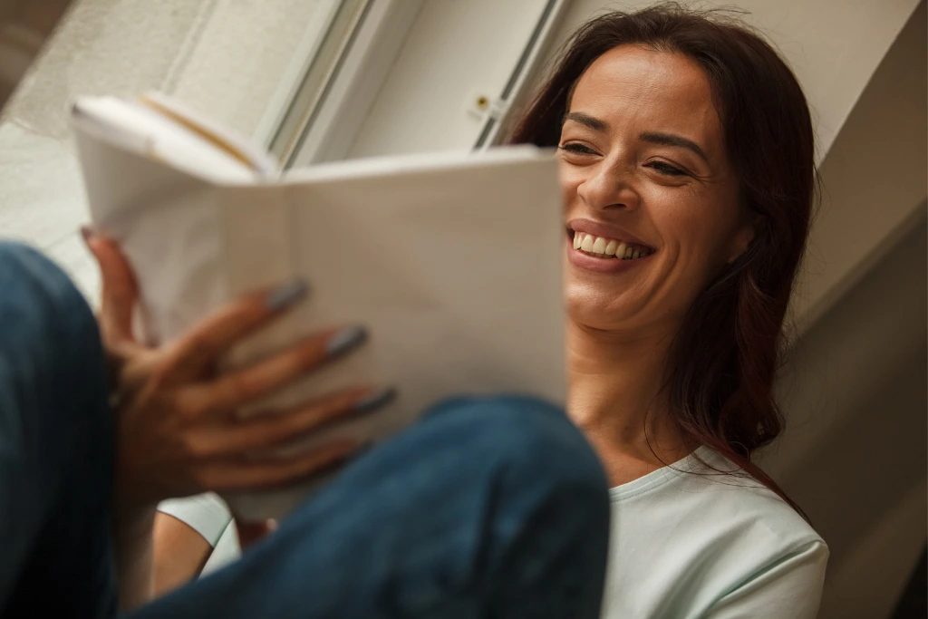 a woman laughing while reading a book