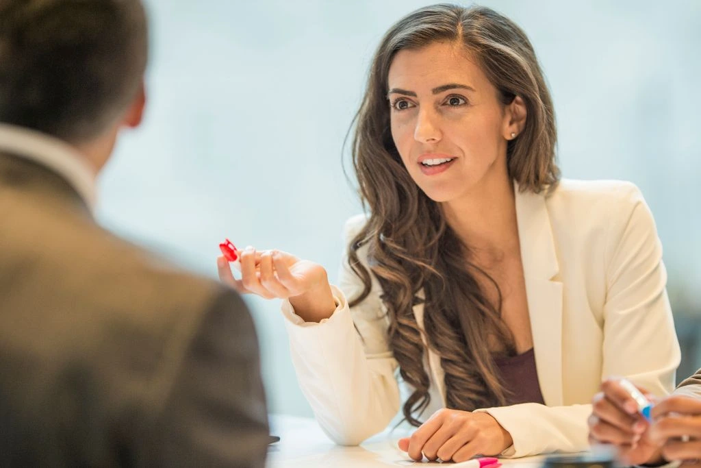 A woman negotiating in a middle of a meeting holding a piece of a product