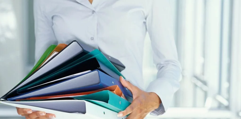Girl in white holding colored folders