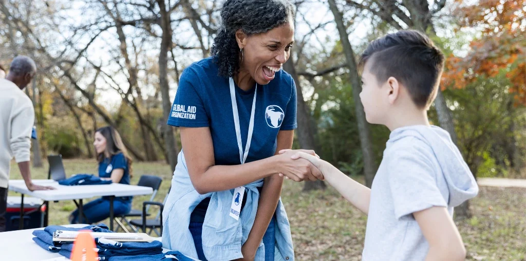 a woman volunteer shaking hands with a young volunteer