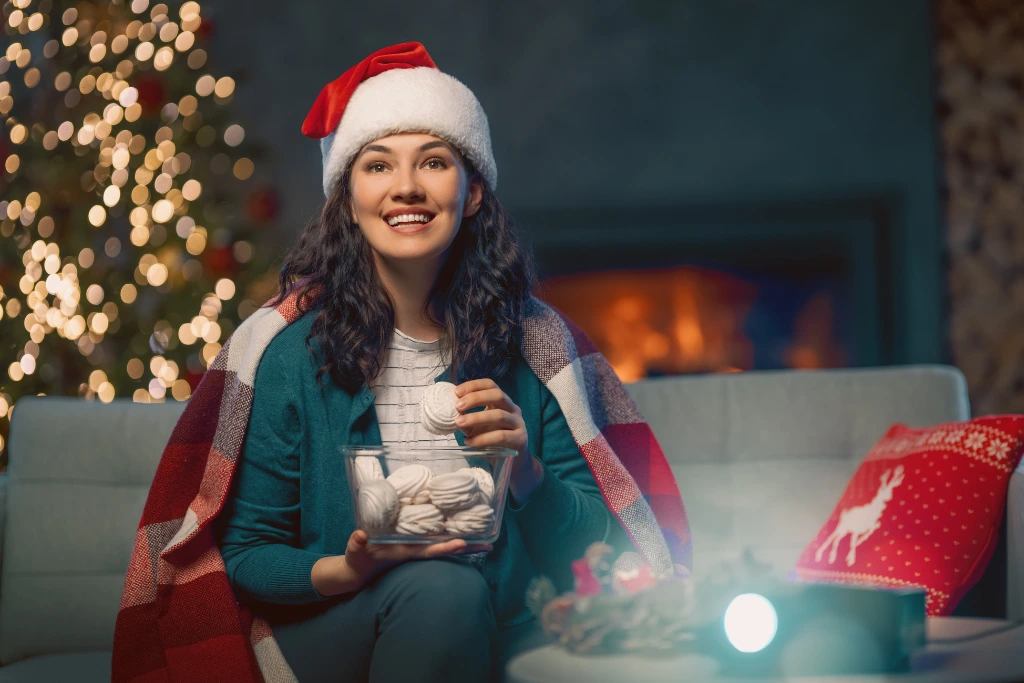 a woman wearing christmas hat eating snacks while watching a movie