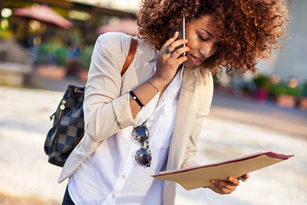 a woman looking at papers while having a call from her mobile phone