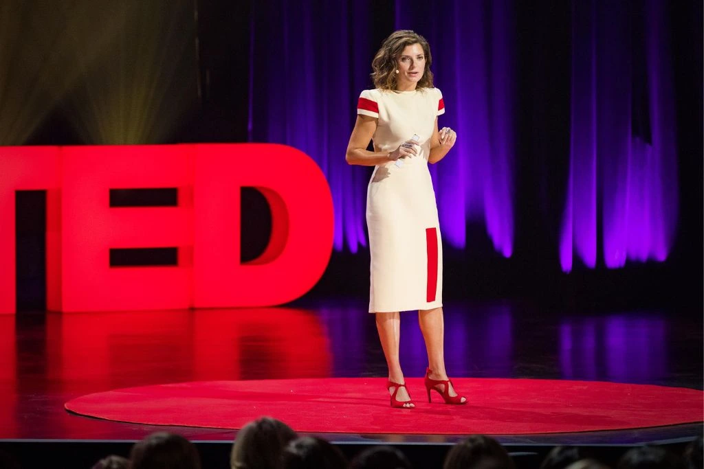 woman standing on tedtalk stage and sharing her speech